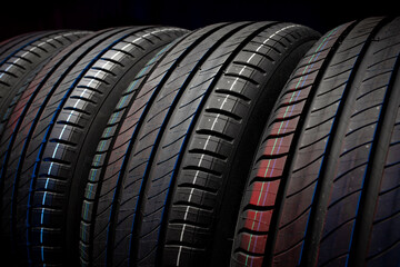 New car tires. Group of road wheels on dark background. Summer Tires with asymmetric tread design. Driving car concept.
