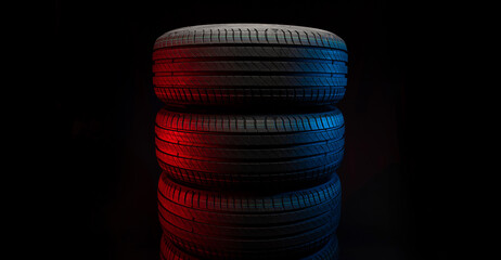 New car tires. Group of road wheels on dark background. Summer Tires with asymmetric tread design. Driving car concept.