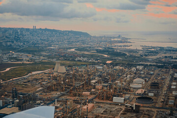 The cityscape of Haifa city and metropolitan area. Aerial Panoramic view from privat aircraft showing large industrial chimneys against houses and port and bay of Haifa Israel 