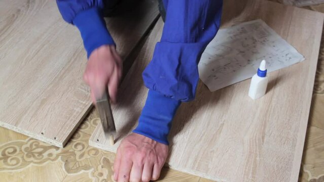 Assembling furniture hammer dowels,carpenter connects kitchen cabinets with wooden dowels