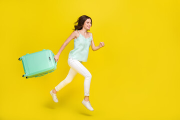 Full body photo of pretty attractive young lady running to airport leaving for summer vacation isolated on yellow color background