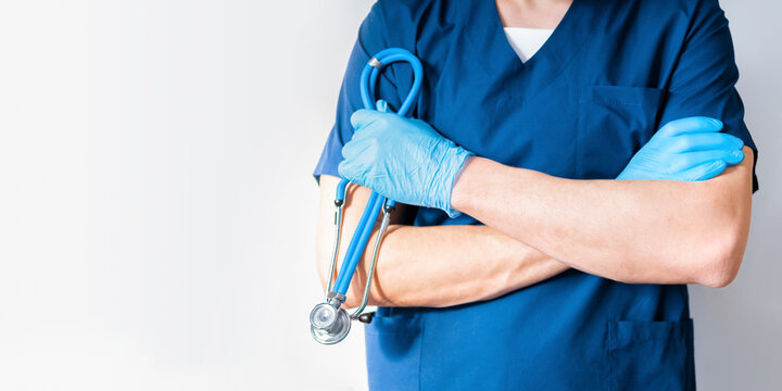 Cropped image of handsome male surgeon doctor with stethoscope in blue uniform in clinic on blue background. banner with copy space