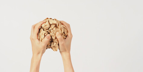 The woman's two hands are holding crumpled brown paper on white background.
