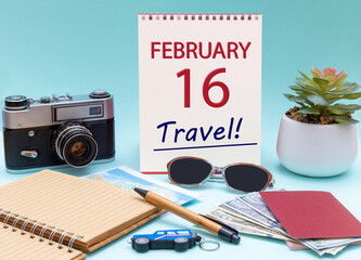 Travel planning, vacation trip - Calendar with the date 16 February glasses notepad pen camera cash passports.