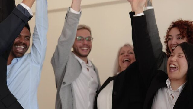 Multiracial business people stacking hands with colleagues inside bank office