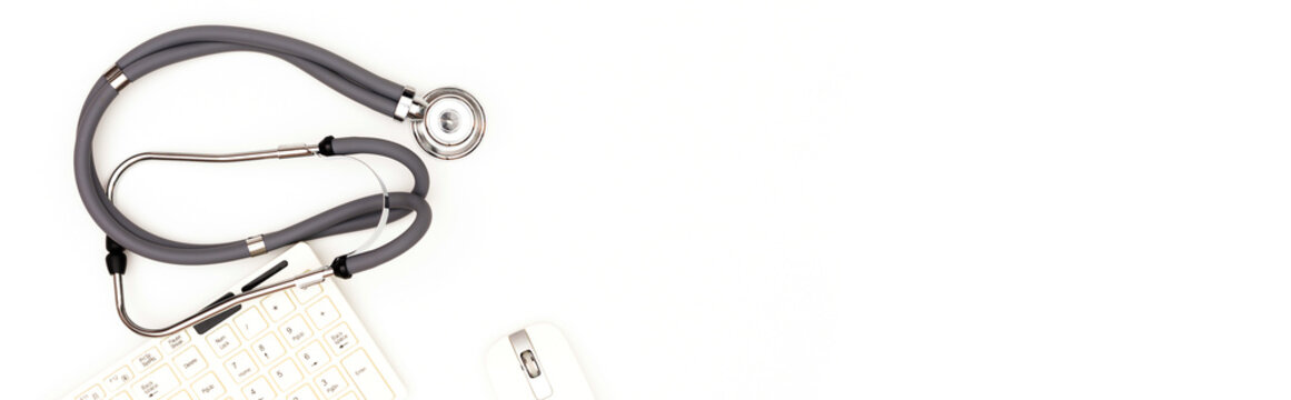 Flatley location. Stethoscope lying near a computer mouse and keyboard, isolated on a white background. Place to copy paste.