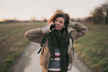 Woman with surprise facial expression  on countryside road having a conversation on phone