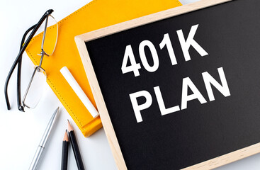 401K PLAN text on the blackboard with notepad , pen, pencil © Iryna