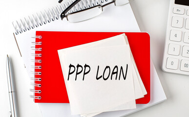 PPP LOAN word on sticker on notepad with pen and calculator