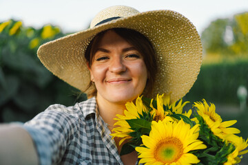Beautiful young woman with sunflowers enjoying nature and laughing on summer sunflower field. Woman...