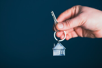 A man in a business suit holds out the keys in his hand.