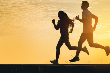 Silhouette of young woman start running at road track. Fit runner fitness runner during outdoor workout with sunset background. Selected focus