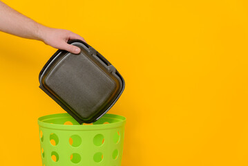 Throw the EPS container into the green trash can for disposal and recycling. Waste collection for recycling, yellow background, space for text.