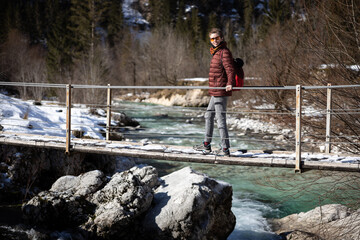 Obraz premium Mid Adult Woman Hiker Discovery Winter Nature Crossing a Suspended bridge 