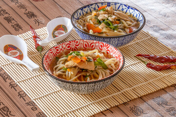 two bowls of thaï style noodle soup with chicken and vegetables, healthy food