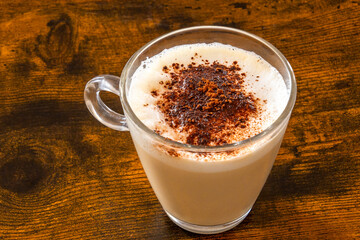 glass of cappuccino on wooden table with chocolate