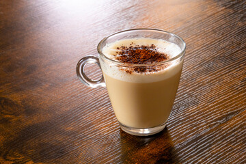 glass of cappuccino on wooden table with chocolate