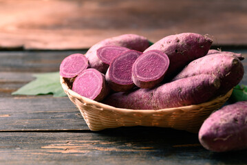 Raw purple sweet potato in basket on wooden background