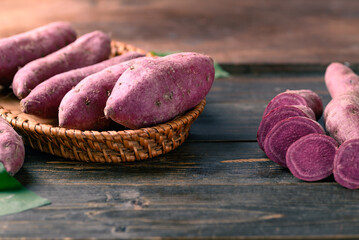 Raw purple sweet potato in basket on wooden background