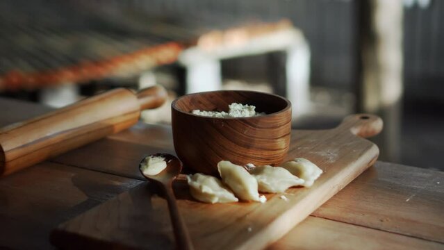 Russian fresh handmade dumplings lying on a wooden table on a cutting board with cottage cheese in a wooden plate