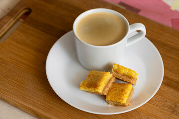A cup of espresso coffee and orange cookies are on the table. Food photo.