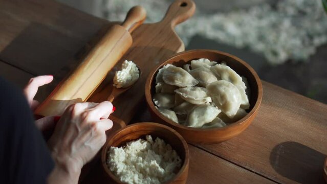 Russian fresh handmade dumplings lying on a wooden table on a cutting board with cottage cheese in a wooden plate