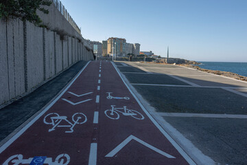 A red bike path along the wall and the ocean.