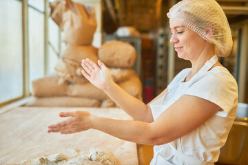 Baker claps flour from her hands while kneading dough