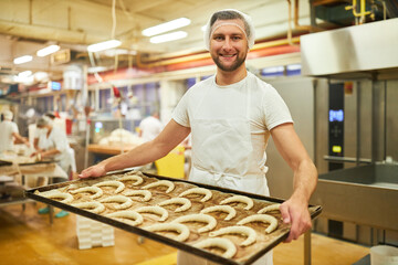 Man is training to become a baker and wears a baking tray