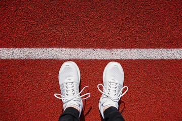 Top view of white male running sneakers near start line at stadium track. Fitness and healthy...