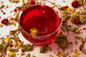 Tea in a glass cup with a rosebud on a background with herbal and flower tea