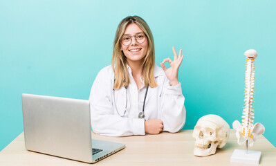 pretty blonde woman feeling happy, showing approval with okay gesture. spine specialist concept