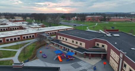 American school buildings at sunrise. Recess playground equipment for students. Aerial view. - Powered by Adobe