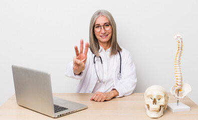 senior  gray hair woman smiling and looking friendly, showing number three. spine specialist concept