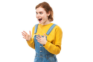 Shocked face red-haired girl looks surprised with open mouth spreads hands on white studio background