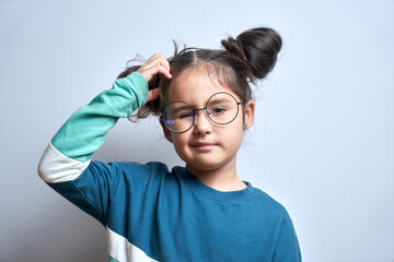 Funny little girl in glasses scratching her head doubts, makes decision isolated on yellow studio background - obrazy, fototapety, plakaty