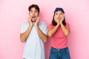 Young couple isolated on pink background surprised and shocked while looking right