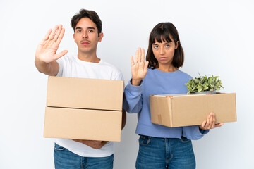 Young couple making a move while picking up a box full of things isolated on white background...