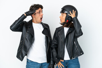 Young mixed race couple with a motorcycle helmet isolated on white background with surprise and shocked facial expression