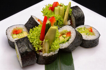 Vegetable sushi roll with cucumber, bell pepper and lettuce, on a white plate