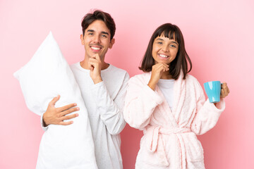 Young couple in pajamas isolated on pink background smiling with a sweet expression