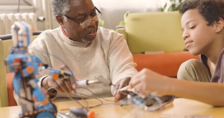 A granddad and his grandchild building a robot at home. - Powered by Adobe