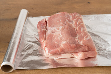 Piece of fresh pork meat lying on sheet of aluminum foil.