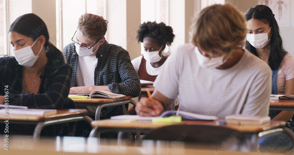 Poster nothing gets in their way of getting that grade. shot of masked teenagers writing an exam in a class