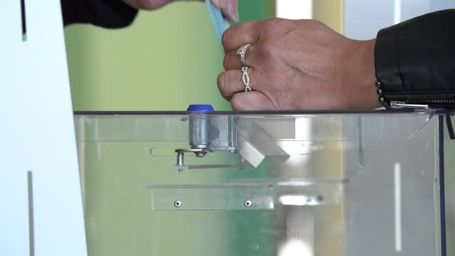A Man Cast His vote into a Ballot Box during Official Election - Close Up