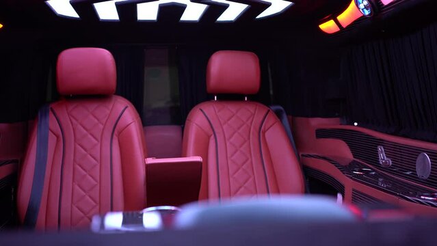 A luxurious car interior of a limousine or business van with red seats and a nice roof lighting. This clip was shot at night to demonstrate the nice LED lighting in this car. The clip is shot in UHD