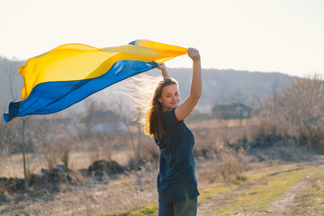 Woman holding a yellow and blue flag of Ukraine in outdoors. Independence Day. Flag Day. Constitution day. Woman in traditional embroidery with flag of Ukraine