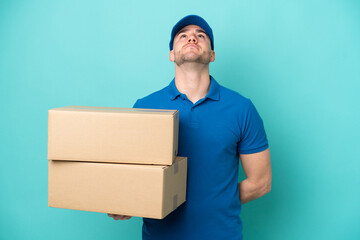 Delivery caucasian man isolated on blue background and looking up