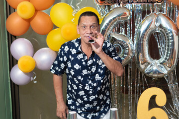 Man with number 60 balloons at birthday party