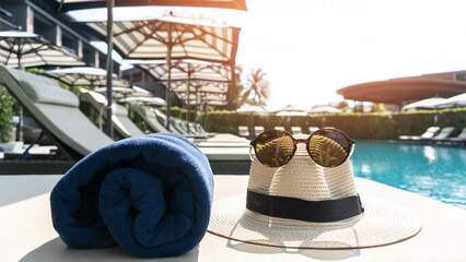 Summer holiday vacation relaxation at resort hotel swimming pool with hat and sunglasses to protect...